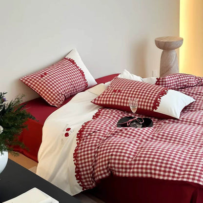 Red and white checkered bedding set on a bed with pillows and a plant.