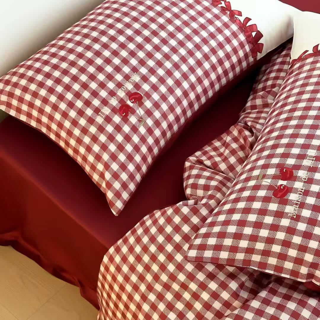 Red and white checkered bedding with embroidered details on a bed.