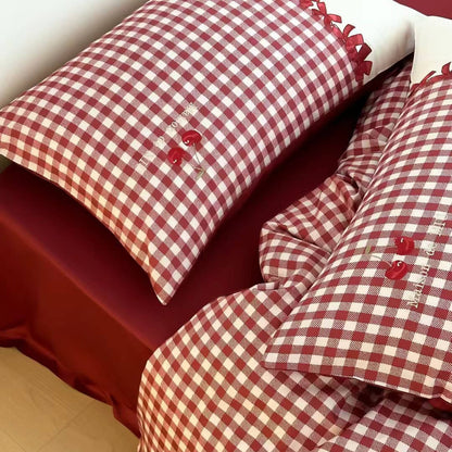 Red and white checkered bedding with embroidered details on a bed.