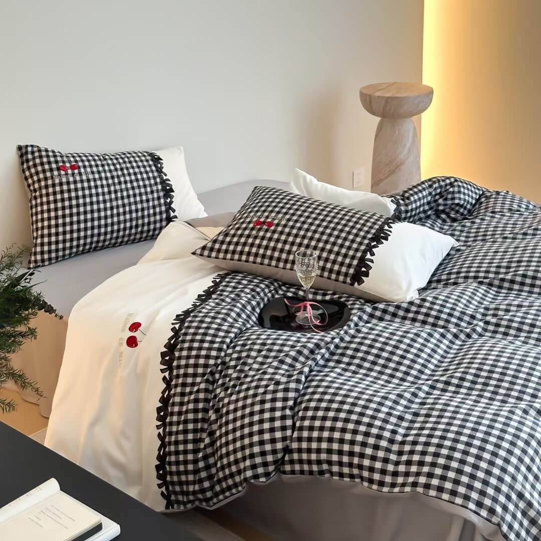 Bed with checkered black and white bedding and pillows, accompanied by a glass of wine on a nightstand.