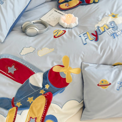 Children's bedding set with airplane design, pillow, and lamp on a bed.