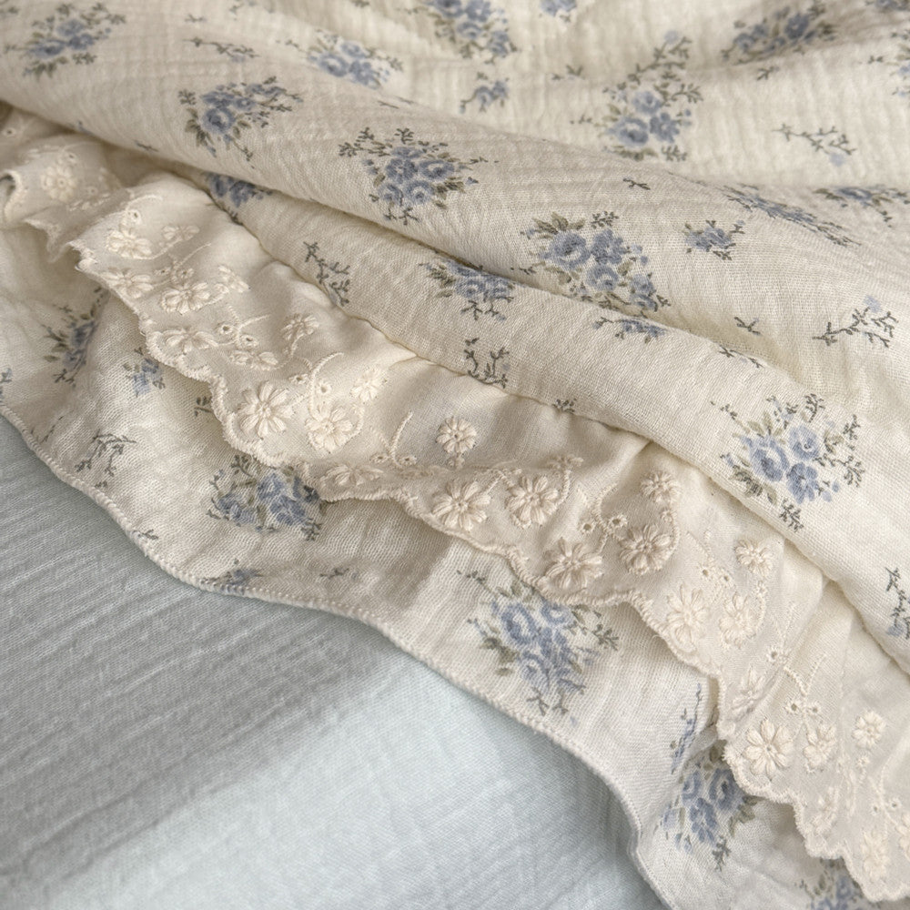 Detailed texture of ruffled lace edge on blue floral cotton comforter