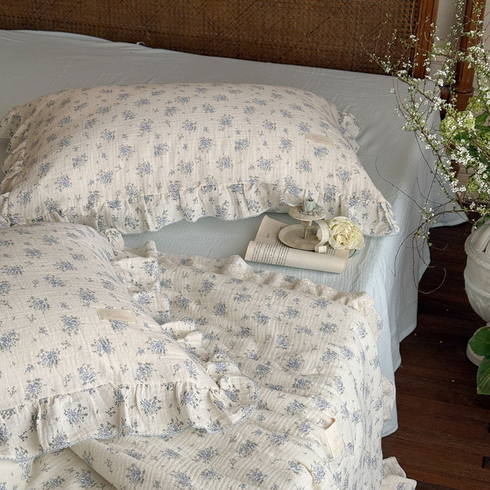 Wide bed scene with soft cotton bedding in light blue and ivory tones