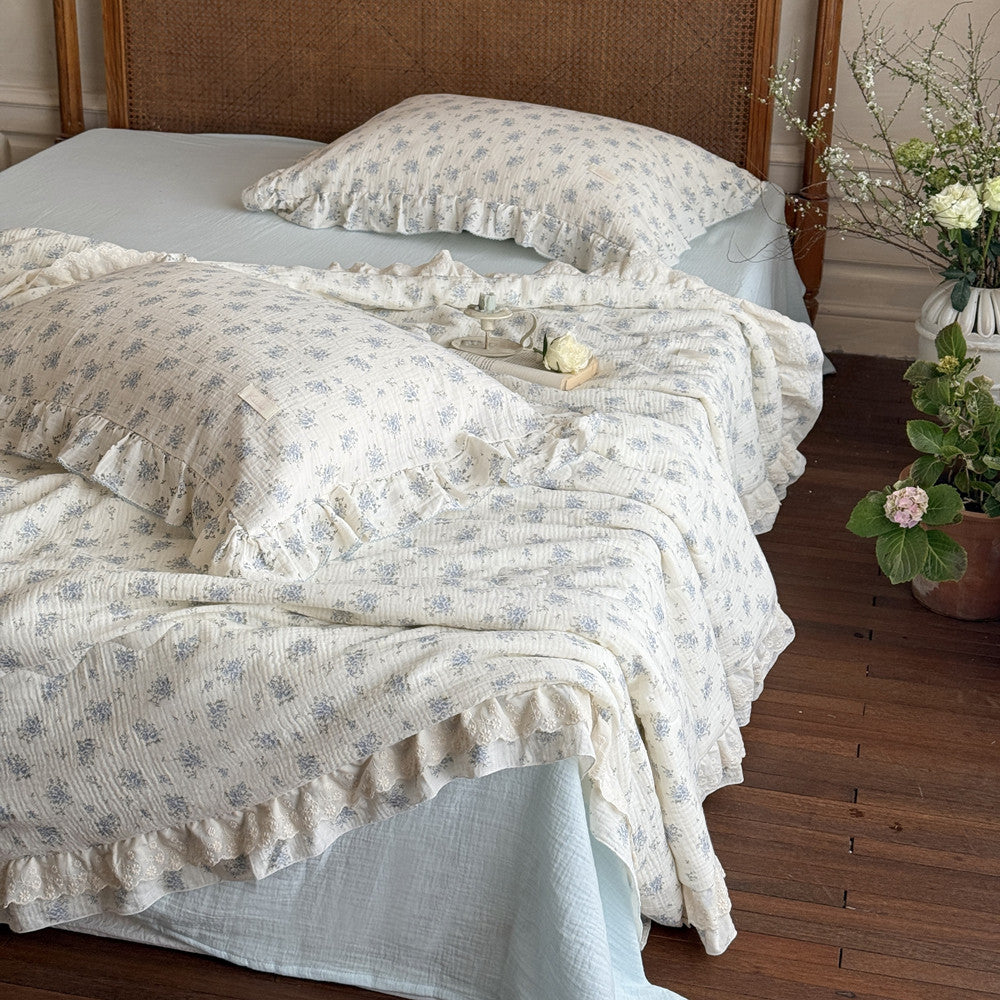 Styled setting of floral ruffled comforter with cozy bedside setup
