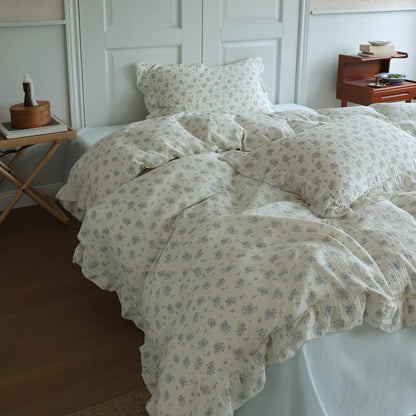 Blue posy bedding styled with soft blue sheet, ruffled trim, and cozy bedroom decor