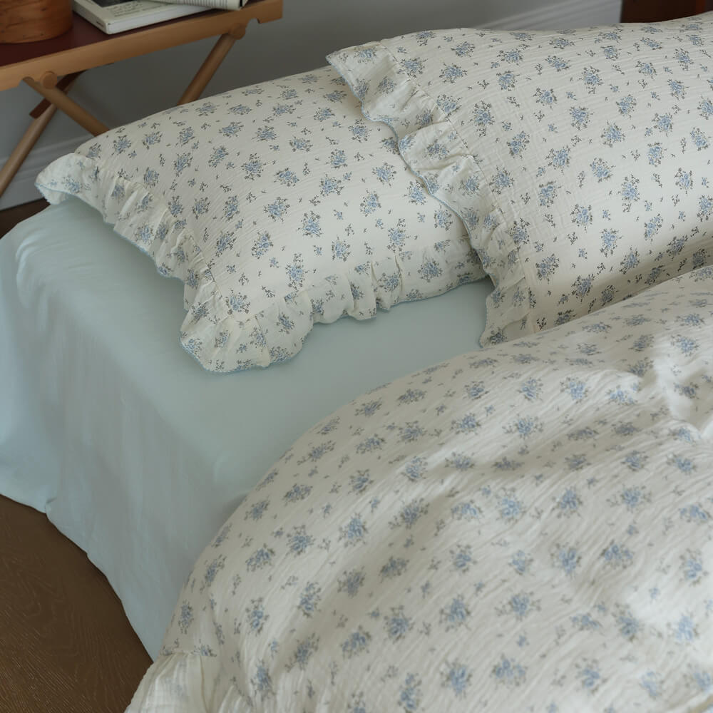Blue posy pillowcases styled with pale blue sheet and ruffled cotton muslin bedding