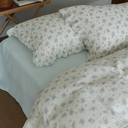 Blue posy pillowcases styled with pale blue sheet and ruffled cotton muslin bedding