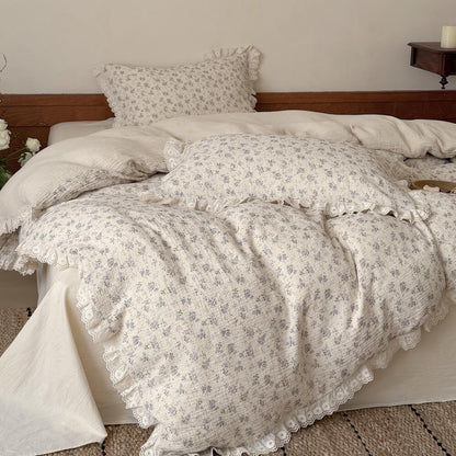 Aesthetic overhead shot focusing on the plump layered pillows and the crinkled texture of a cottagecore blue floral comforter, styled on a neutral linen sheet with warm natural lighting.