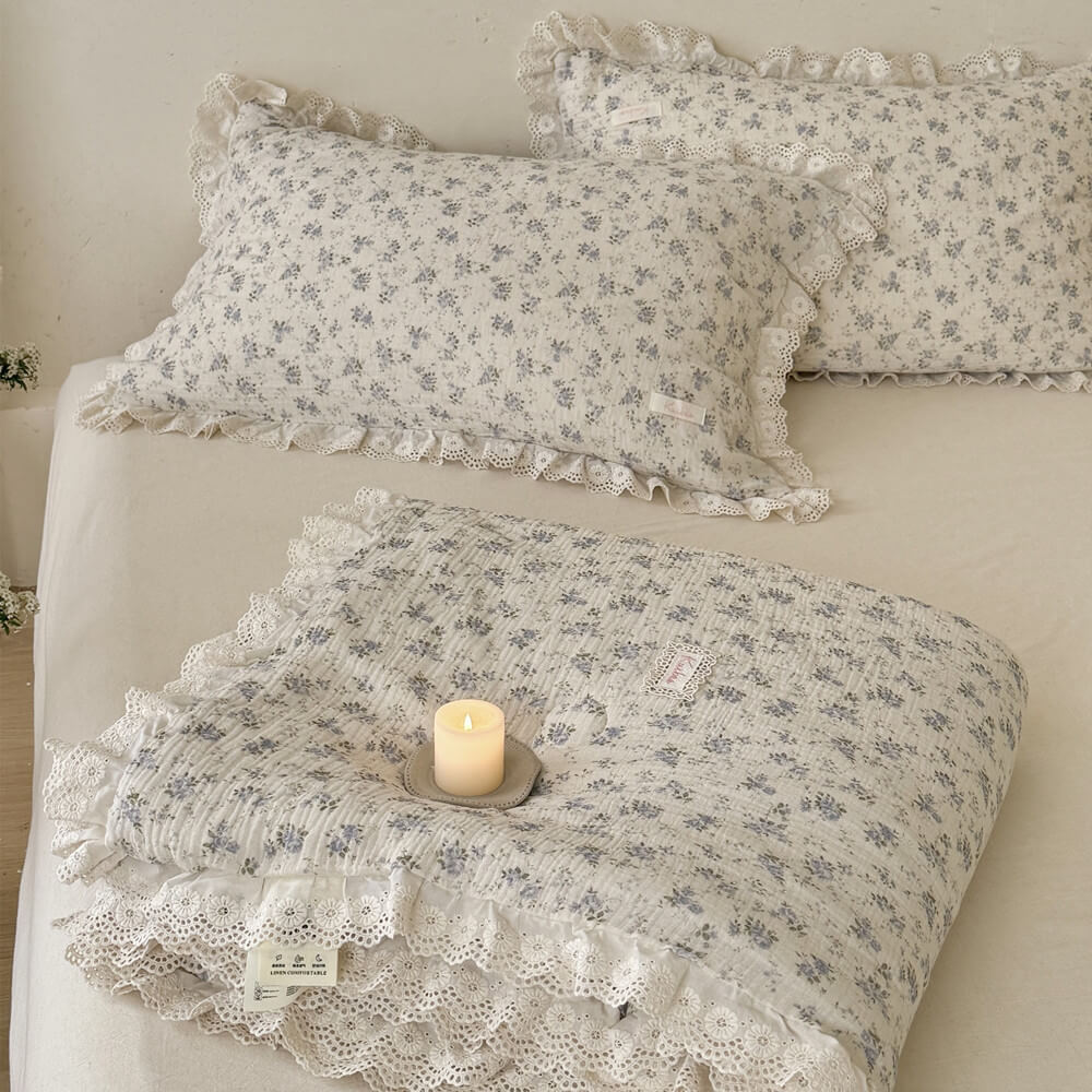 Neat square-folded blue rose muslin comforter with scalloped lace trim placed on a bed, highlighting the soft fabric texture and premium cottagecore design.