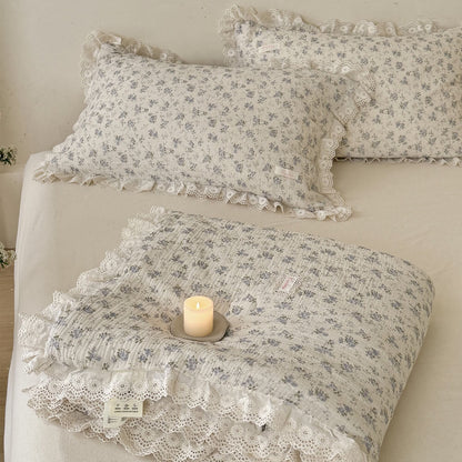 Neat square-folded blue rose muslin comforter with scalloped lace trim placed on a bed, highlighting the soft fabric texture and premium cottagecore design.