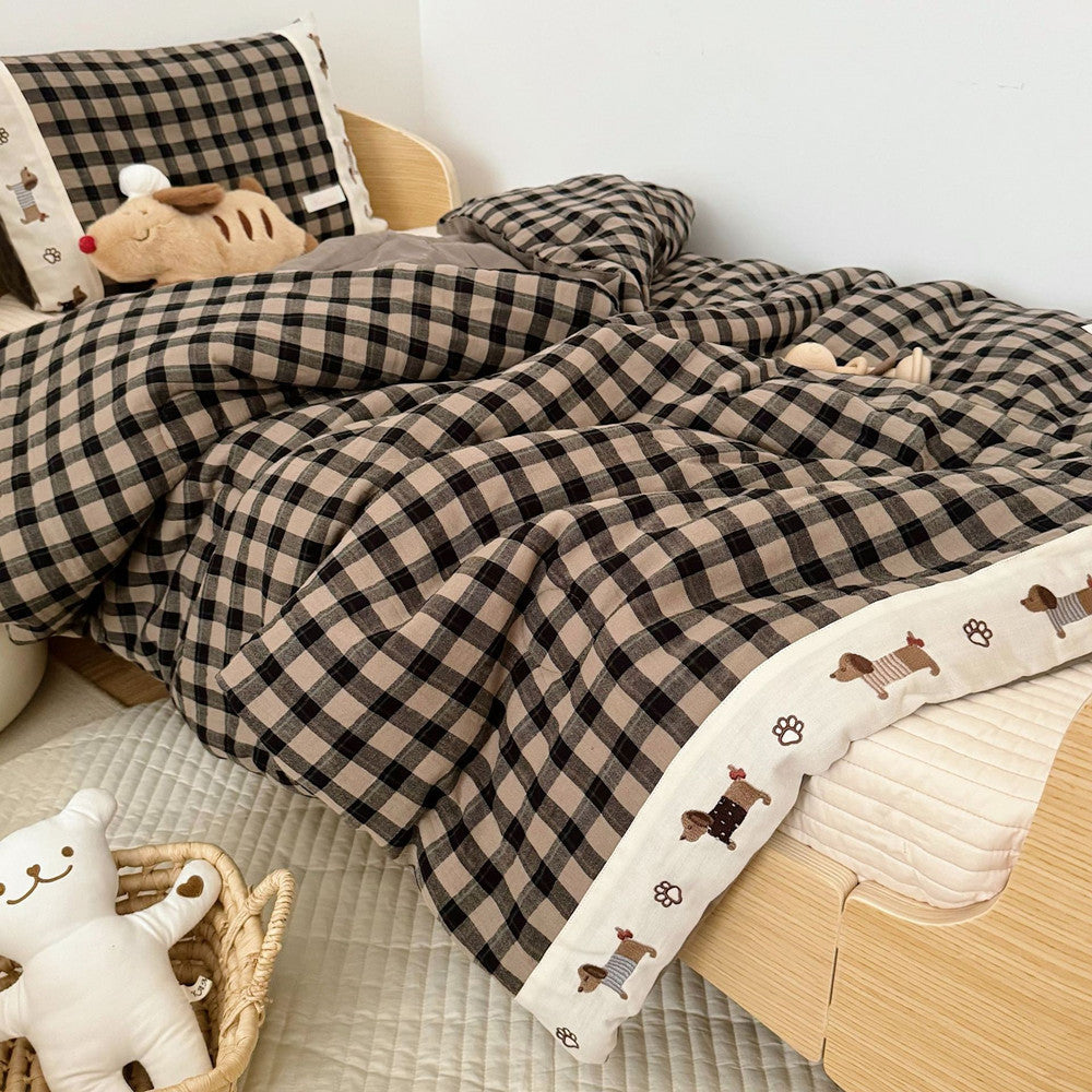 Plaid blanket with dog paw prints on a bed in a bedroom setting
