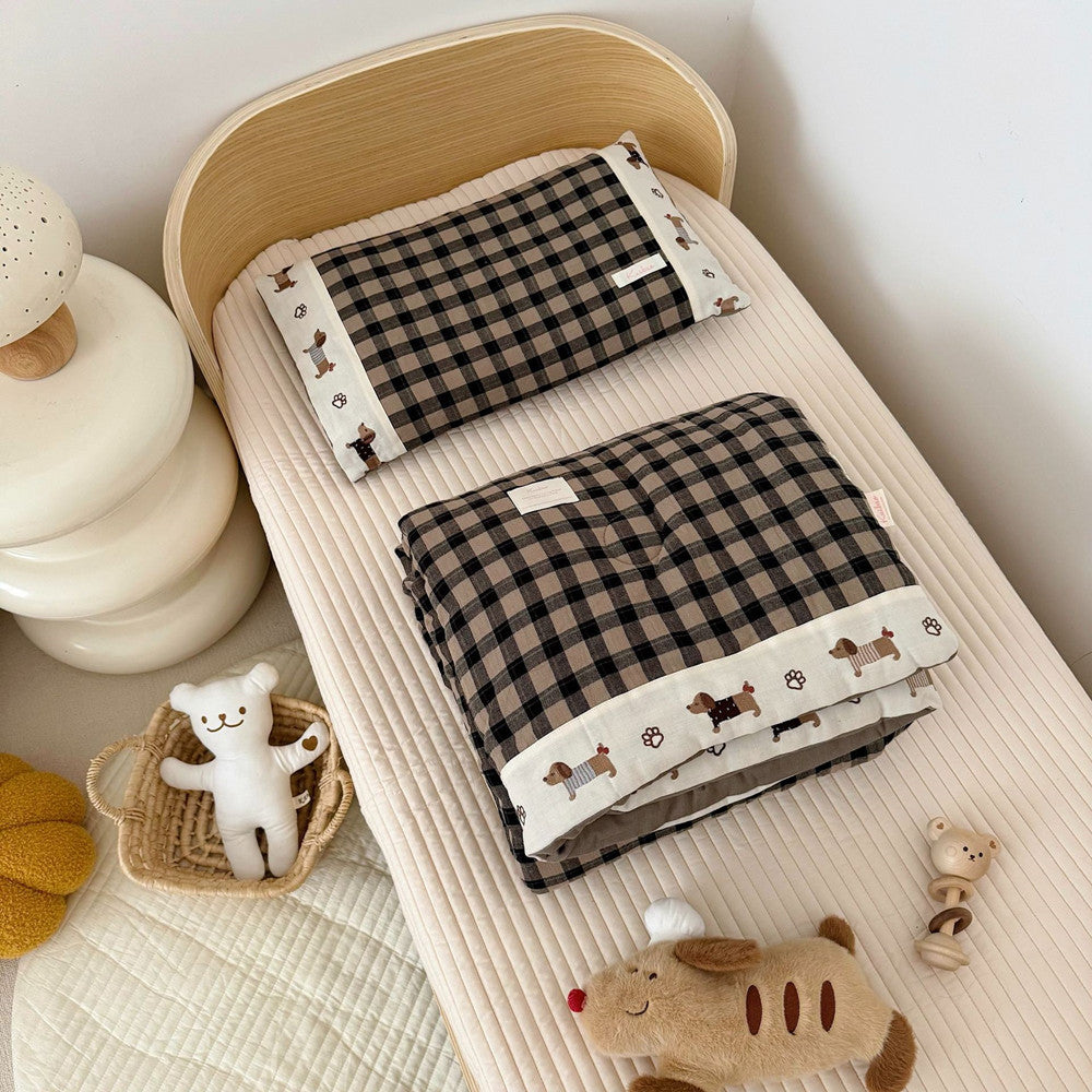 Checkered comforter and pillow set on a crib with toys in a nursery setting.