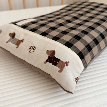 Checkered pet bed with embroidered dog designs on a white surface