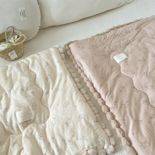 Two cotton comforter with bunny patterns on a light surface.