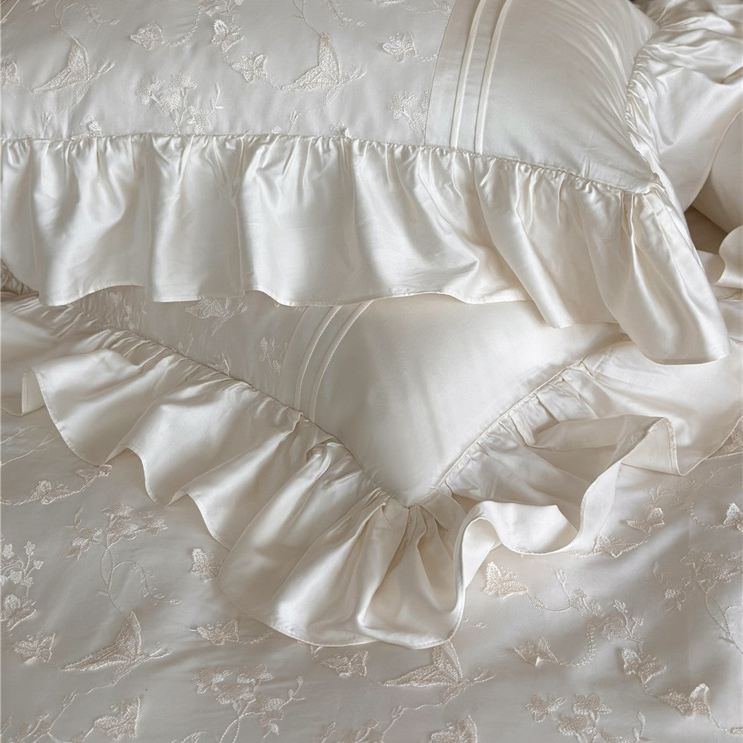 Detail of stacked cream pillows from the Butterfly Embroidered Bedding Set with ruffles.