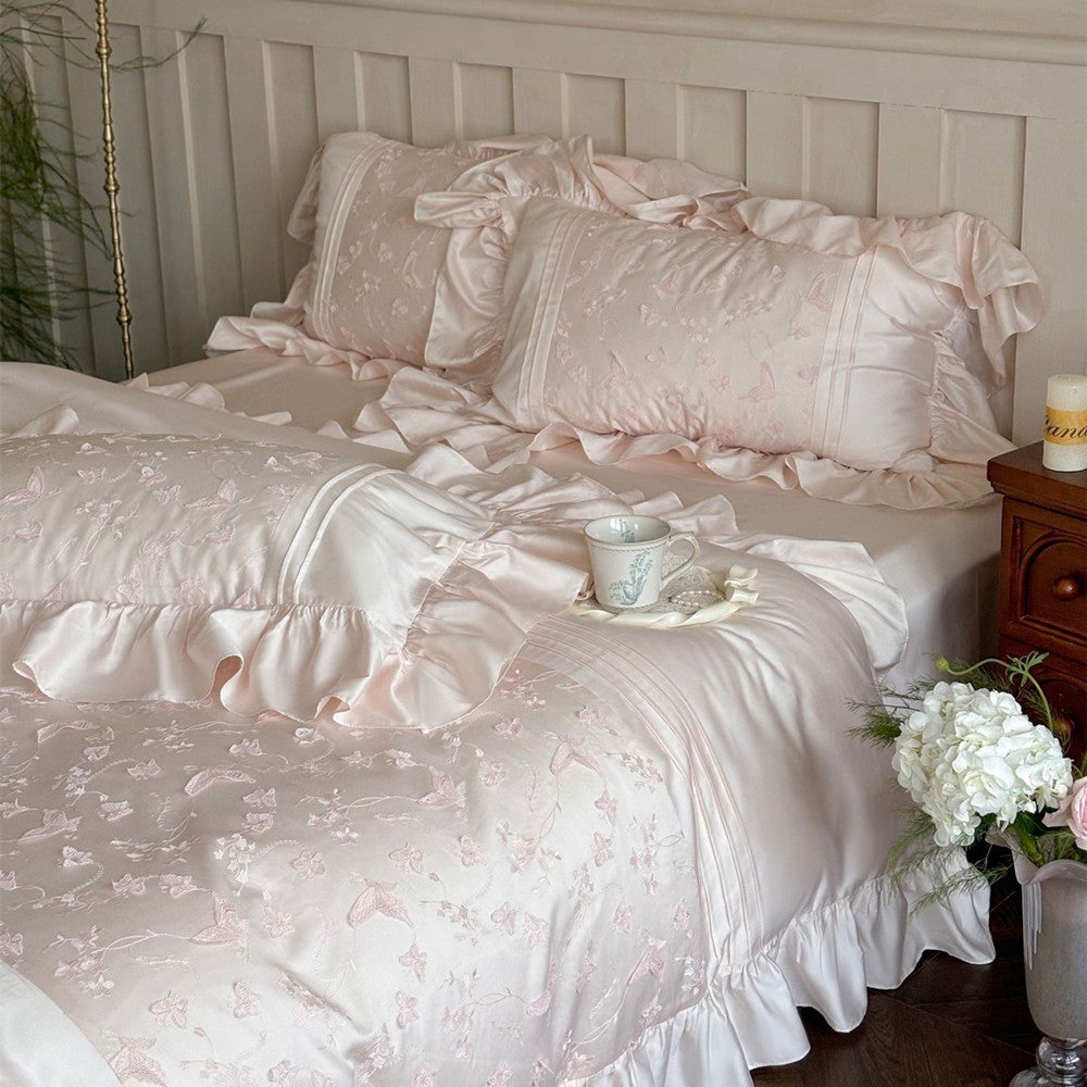 Pink Butterfly Embroidered Bedding Set featuring ruffles on the duvet and pillows in a bedroom scene.