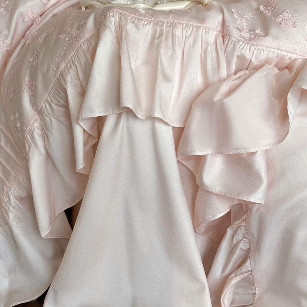 Texture close-up of the silky Tencel fabric and deep ruffles on the pink bedding.