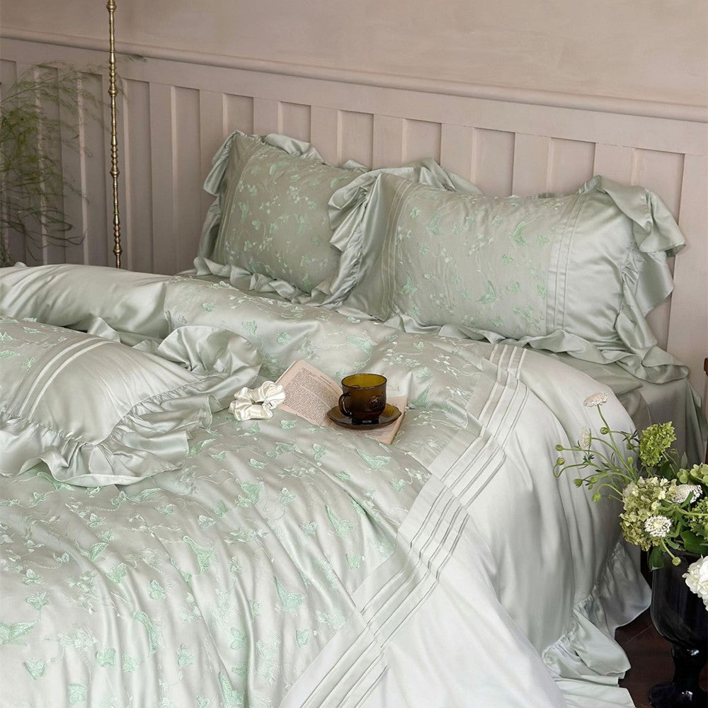 Overhead view of the light green Butterfly Embroidered Bedding Set and pillows with ruffled edges.