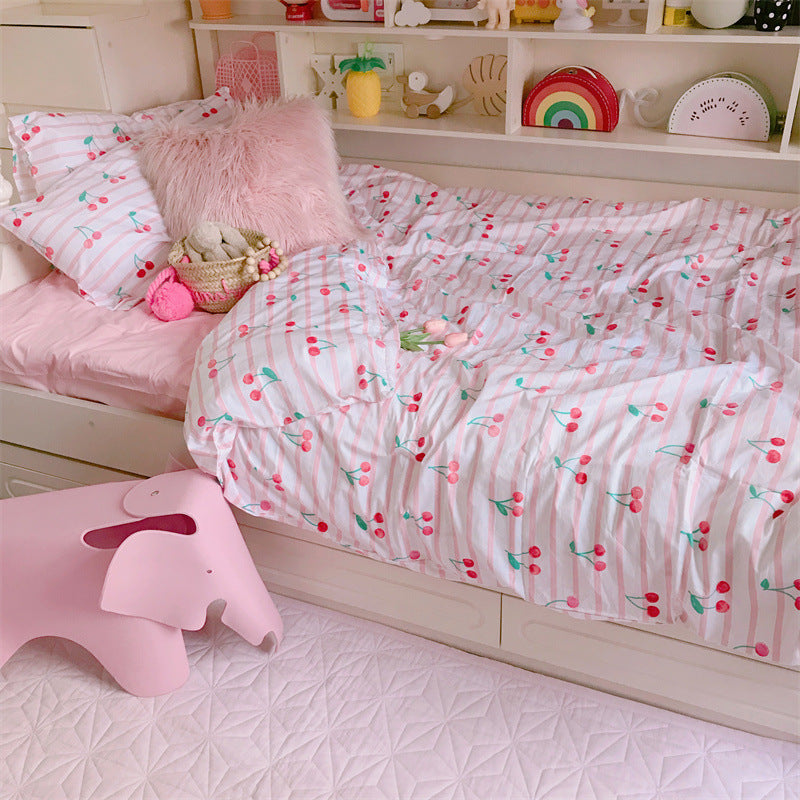 Children's bedroom with cherry-patterned bedding, pink elephant stool, and shelves with toys.