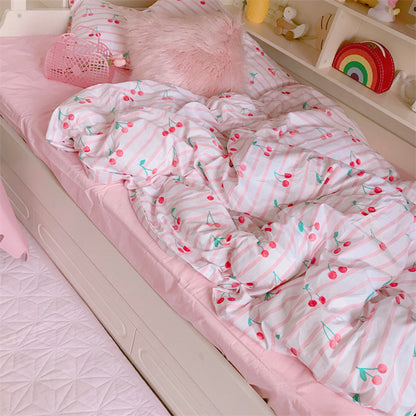 Children's bed with pink cherry-patterned comforter and toys on a shelf.