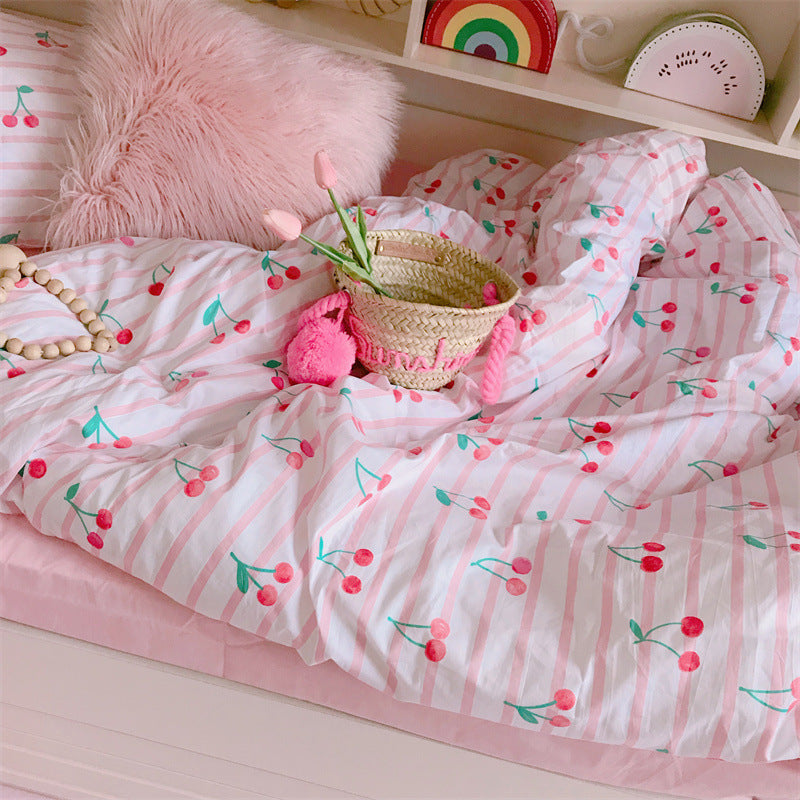 Children's room with pink cherry-patterned bedding and decorative items.