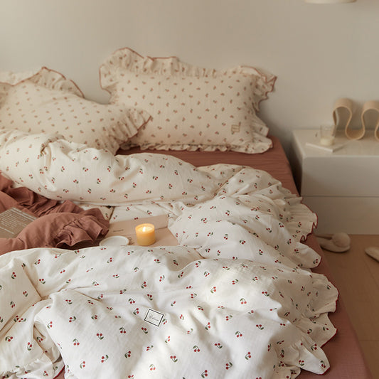  soft cotton muslin bedding set with a cherry print and ruffle trim, including a duvet cover and pillowcases, displayed on a bed.