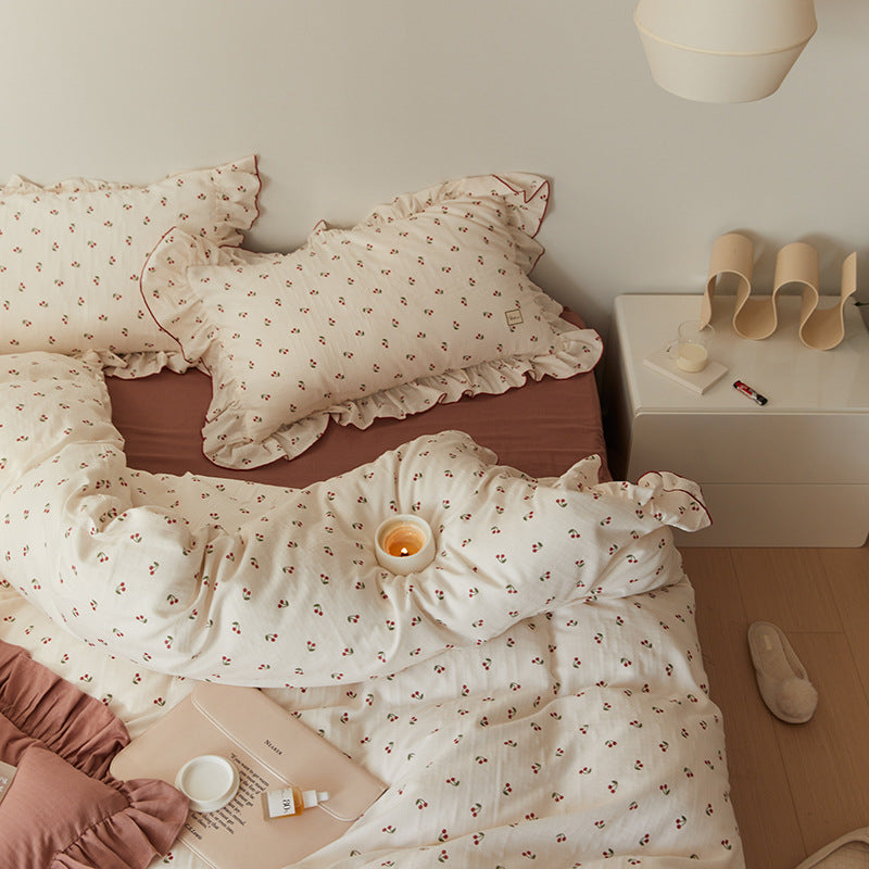 A close-up view of the bed, showcasing the cherry-print cotton muslin duvet cover and matching pillowcase with ruffle trim.