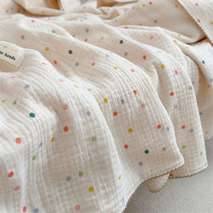A side shot of the Colorful Dot muslin blanket, emphasizing its lightweight, breathable fabric and its colorful dots on a quilted surface.