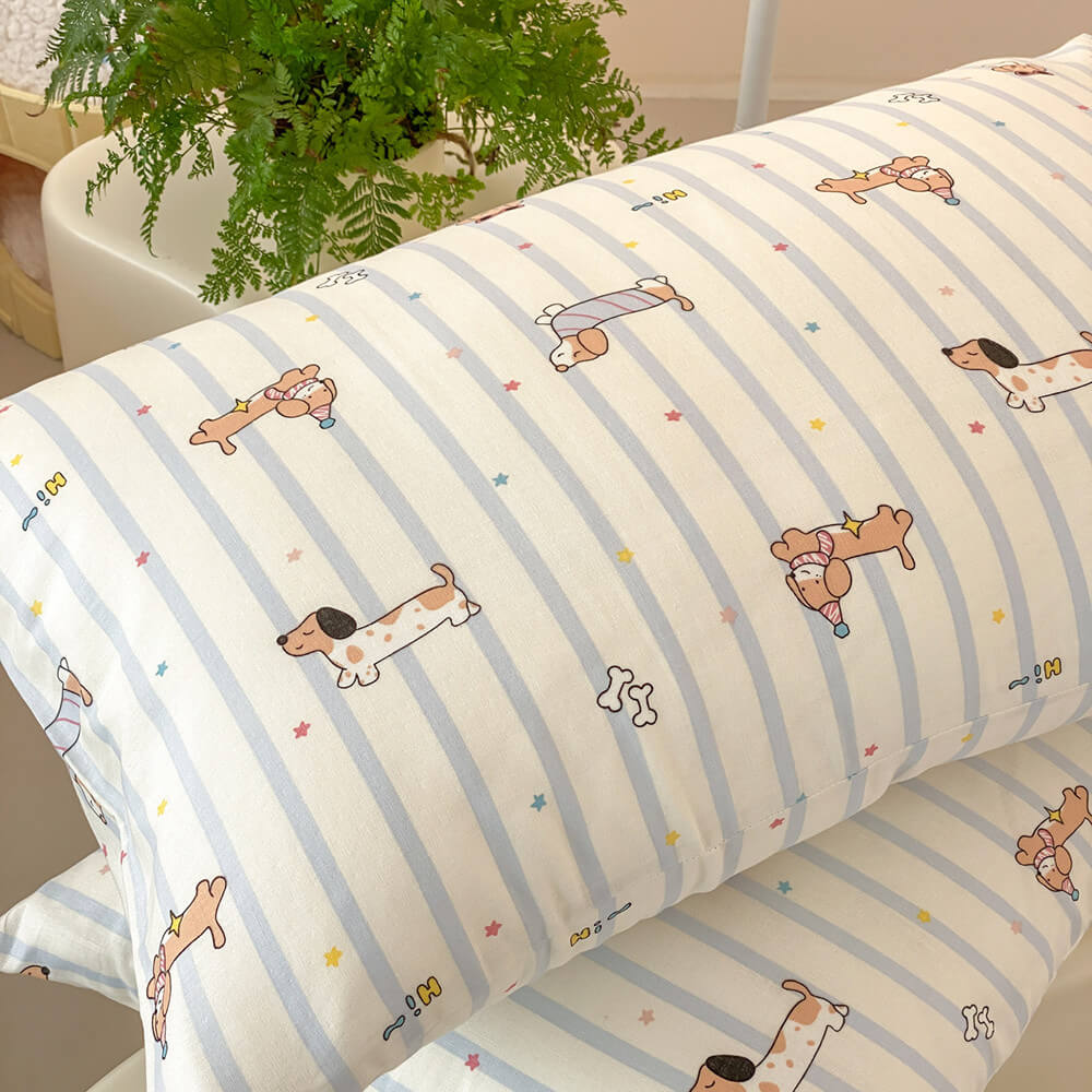 Close-up of dachshund stripe pillowcase with pale blue stripes, dog illustrations, colorful stars, and cotton muslin texture
