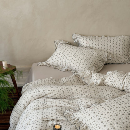 A full view of a bed styled with a cotton muslin duvet cover set, showing the ruffled pillowcases and duvet cover.