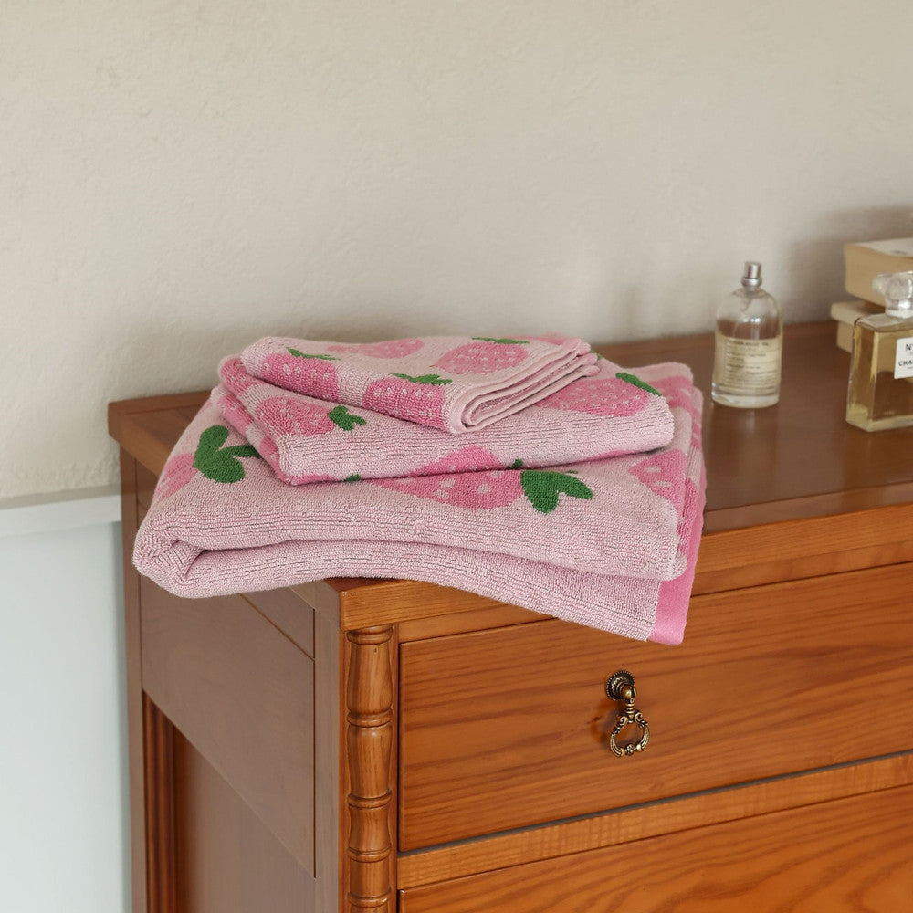 Pink strawberry towel set folded with washcloth, face towel, and bath towel