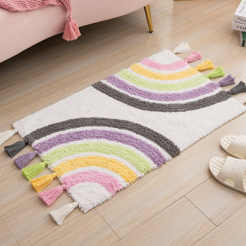 Cotton rainbow area rug with tassels, sized 50x80cm, placed in a modern living room setting near a pink sofa.