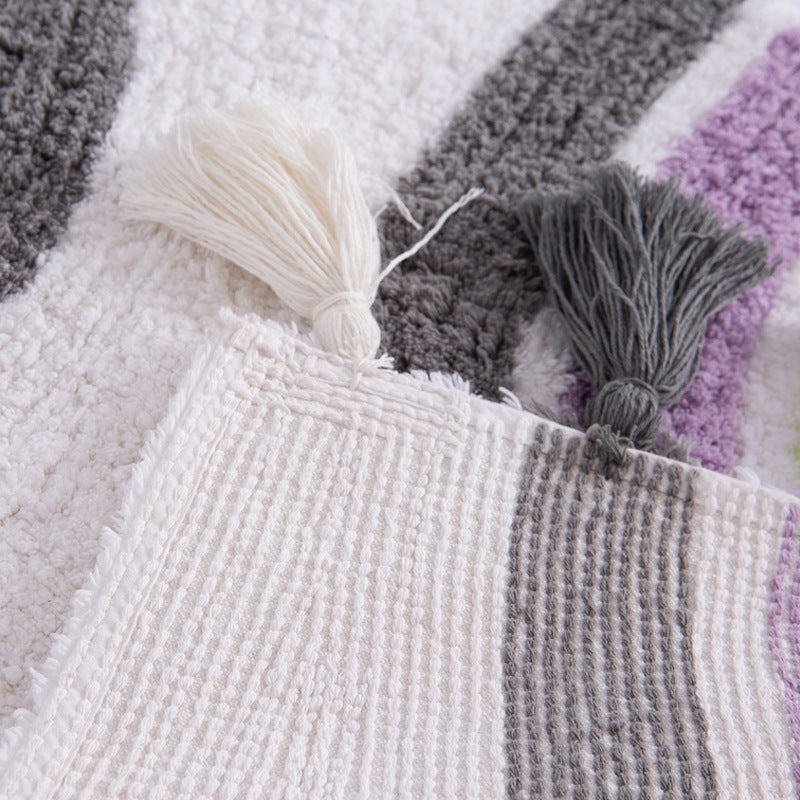 Close-up view of the handmade cotton tassels and textured woven pattern for backside of the 50x80cm rainbow area rug.