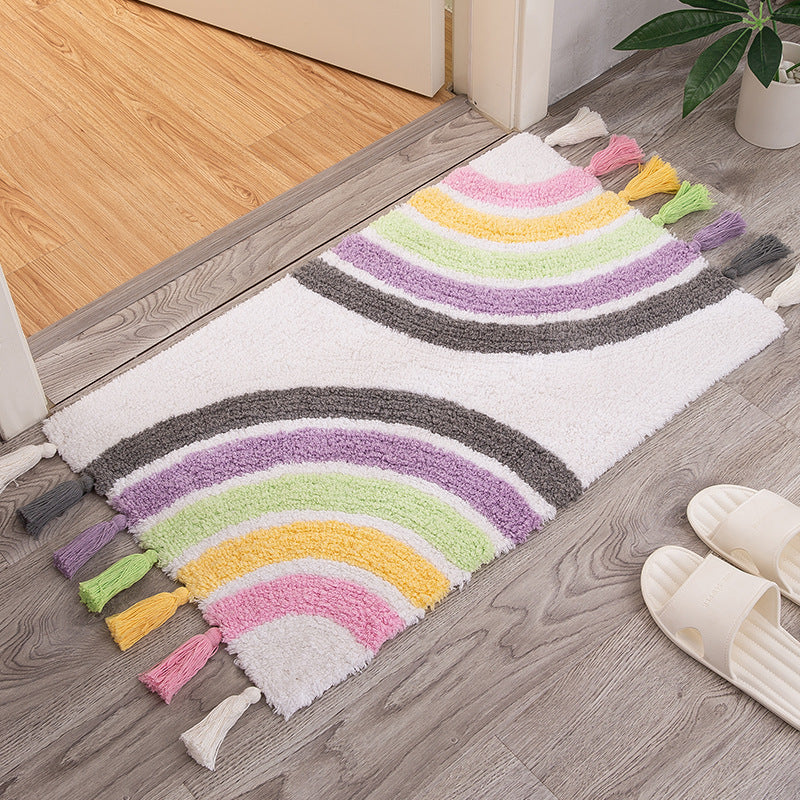 Colorful cotton rainbow area rug with tassels, sized 50x80cm, placed on a wood floor in a home entryway or doorway.