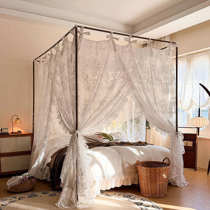 Bedroom with a canopy bed draped in lace curtains, wooden nightstands, and a lamp.