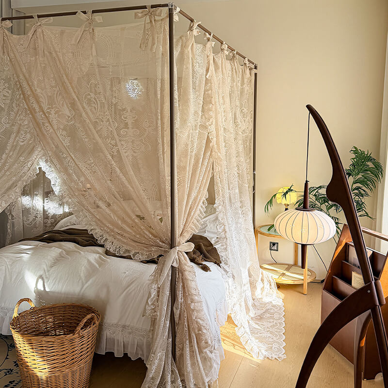 Bedroom with a canopy bed draped in lace curtains, a chair, and a lamp.