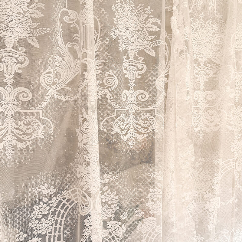 Close-up of lace fabric with intricate patterns in neutral tones.