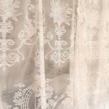 Close-up of lace fabric with intricate patterns in neutral tones.