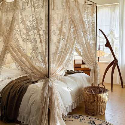 Bedroom with a canopy bed draped in lace curtains, wooden nightstands, and a wicker basket.