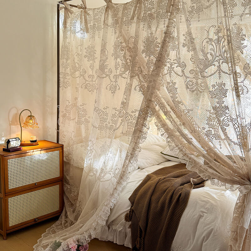 Bedroom with a canopy bed draped in lace curtains, wooden nightstand with lamp.