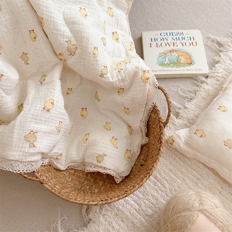 White fabric with gold animal prints in a wicker basket on a soft surface
