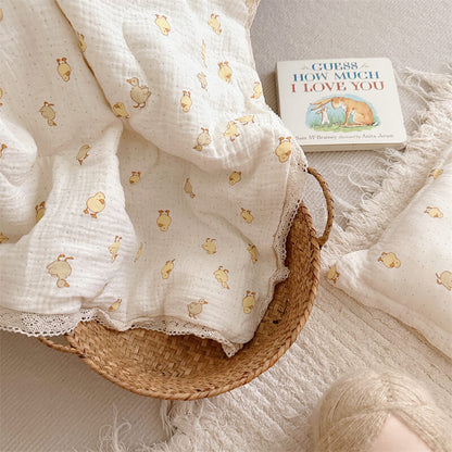 White fabric with gold animal prints in a wicker basket on a soft surface