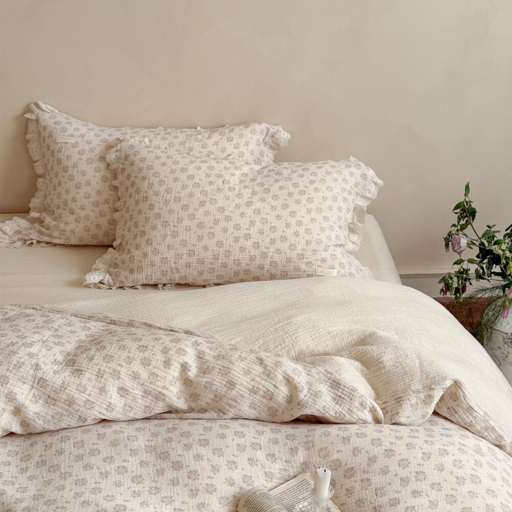 Shabby chic bedding arrangement showcasing a cream white and dusty pink ditsy floral print comforter paired with matching vintage lace-trimmed shams.