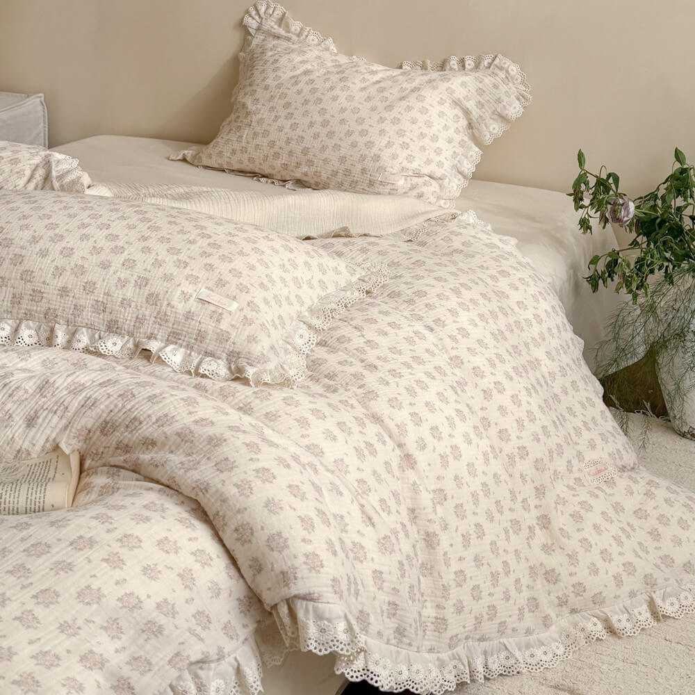 Detailed view of a layered Victorian style bed featuring a premium breathable muslin cotton dusty pink floral duvet cover and intricate embroidery lace edges.