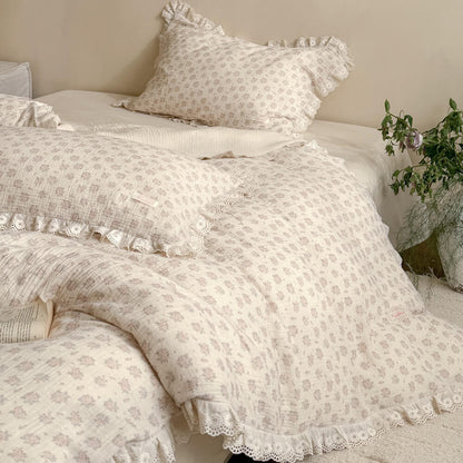 Detailed view of a layered Victorian style bed featuring a premium breathable muslin cotton dusty pink floral duvet cover and intricate embroidery lace edges.