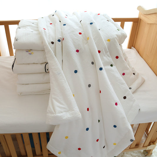 embroidered cotton baby quilt with  colorful polka dots, displayed on a crib