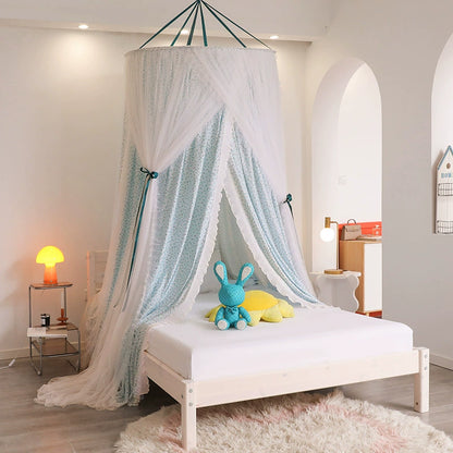 Kids bed canopy in light teal floral fabric and white sheer tulle, suspended over a single wooden bed with white sheets and a blue plush toy.
