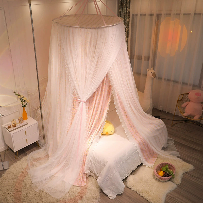 Pink princess fabric canopy with a delicate floral print, draped over a small white bed, featuring sheer white netting tied back with pink ribbons.