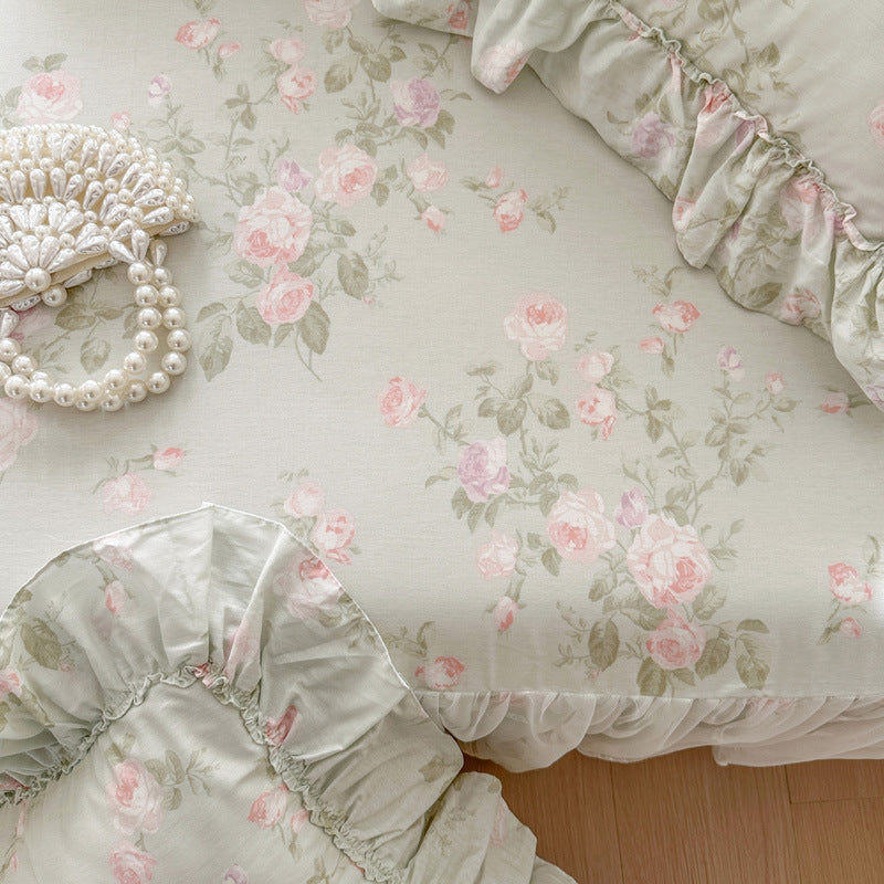 Floral patterned fabric with pink roses and green leaves on a light background.