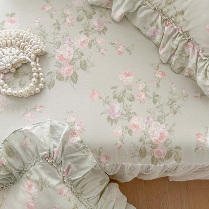 Floral patterned fabric with pink roses and green leaves on a light background.
